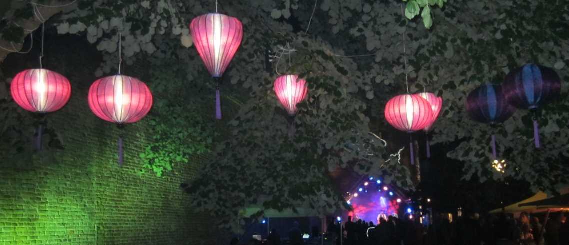 Lilafarbene Lampions in Bäume gehängt auf einem Gartenfest